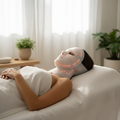 Person receiving LED facial and neck mask red light therapy treatment